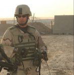 Photo of James Ramondetta in desert camouflage uniform with a German Shepard K-9.