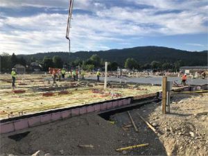 Construction photo of a concrete slab pour. Blue skies, trees and hills in the background