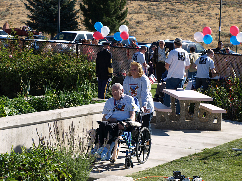 Veteran's Olympics Outside with balloons and Woman pushing Man in Wheelchair